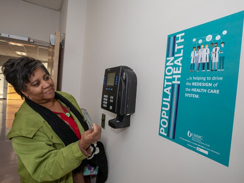 Jessica Eglin, a pediatric neonatology administrative assistant, uses the time clock near R153. Posters for the School of Population Health's BINGO game are located in several high-traffic areas on campus.