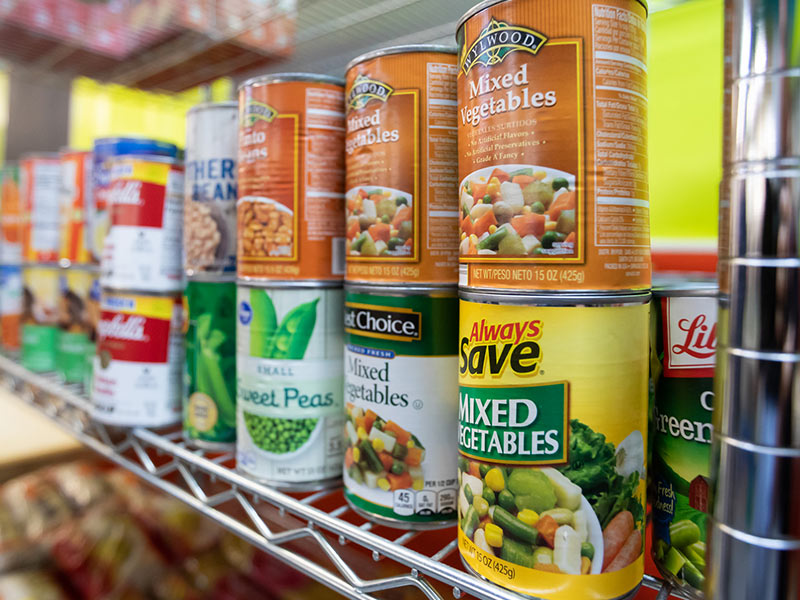 Cans of food stacked on shelf.