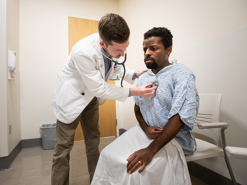 Medical student Jeffrey Farrington examines Standardized Patient Randall Bolden.