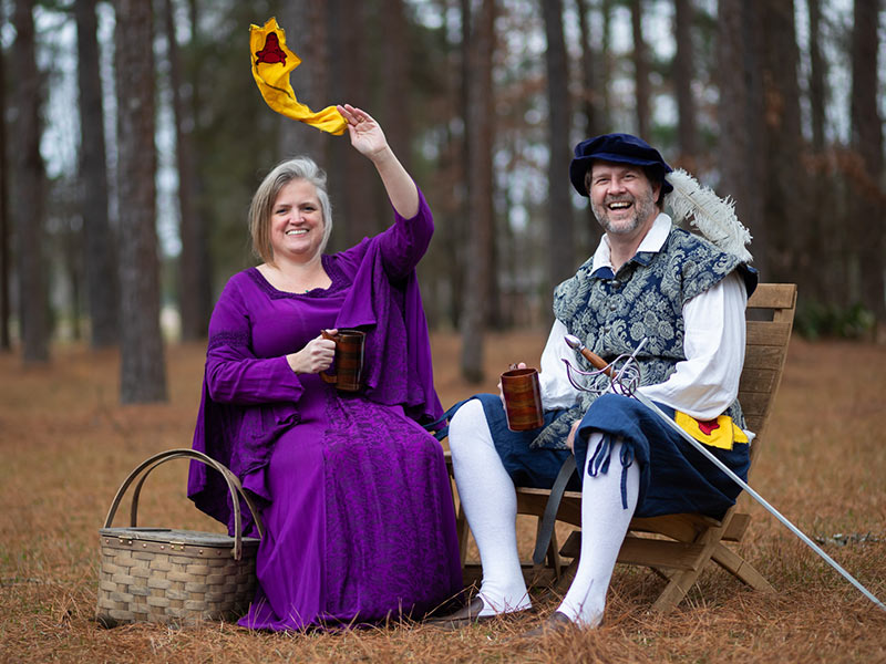 Alana Bowman waves the banner for the Shire of Iron Ox, the local SCA chapter, while Dr. Jason Griggs smiles.