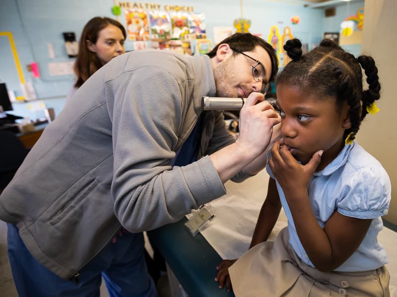 Third-year medical student Brandon Bush examines 1st grader Leilani Gray's right ear as part of a well-child screening.
