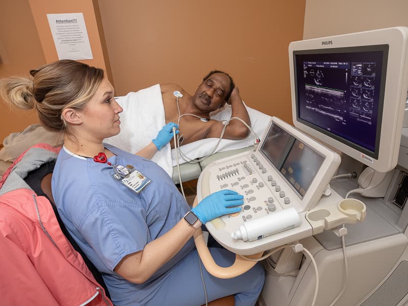 Cardiology sonographer Heather Edgar examines images of the heart of Lucious Thomas, who underwent a procedure to repair his mitral valve in January.