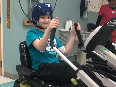 Corbin during physical therapy on exercise bike.