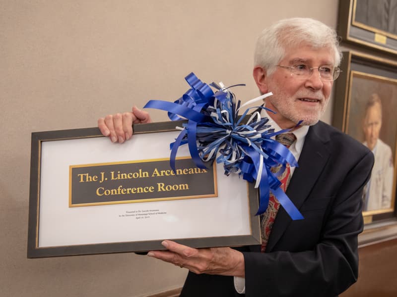 Dr. Lincoln Arceneaux accepts a framed representation of the plaque marking the room named for him.