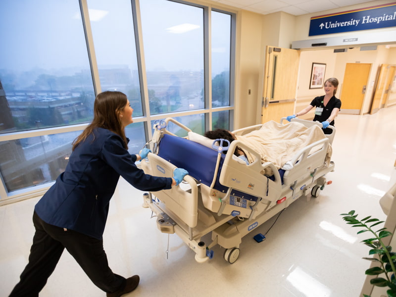 Registered nurses Allen Spencer, left, and Shelby Dye transport a patient from the SICU to a room in the adult hospital, where they will hand off the patient's care to another nurse.