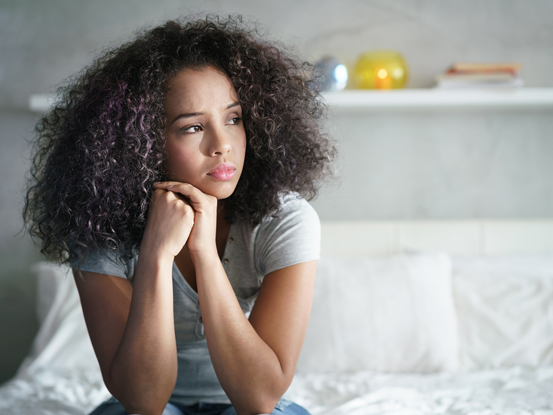 Woman looking off to the side with head on hands.