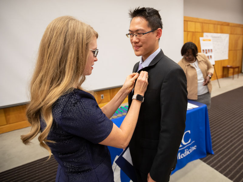 Dr. Lyssa Weatherly, the Gold Humanism chapter's faculty advisor, presents a lapel pin to Dr. Michael Yeung-Lai-Wah, a family medicine resident.