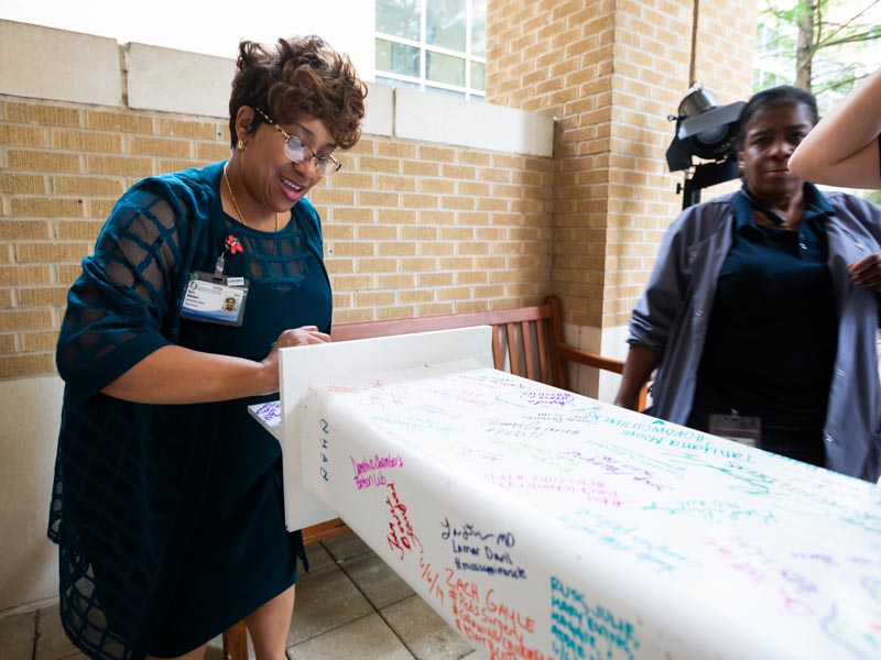 Doris Whitaker, left, director of Pastoral Services at UMMC, signs her name to the beam.