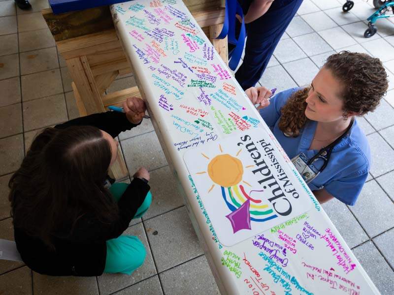 Peds resident Carroll Anna Troy, right signs the beam.