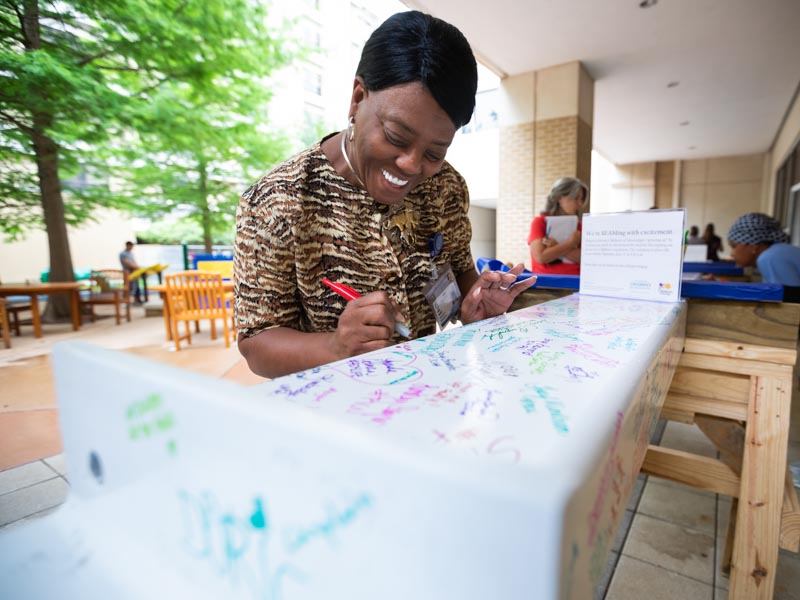 Cathy Randall, business analyst in anesthesiology, signs the beam during the June 6 signing party.