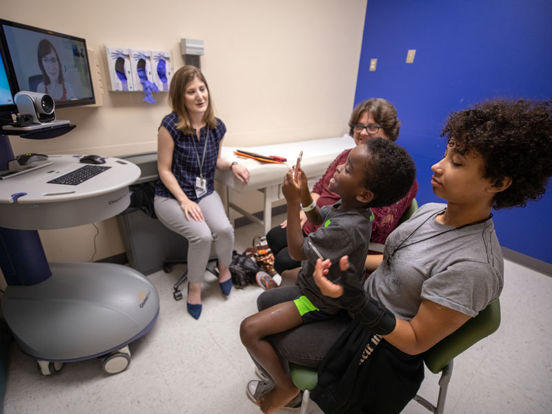 Dr. Kimberly McDonald, left, a pediatric geneticist, speaks with Elizabeth Barber about her son Jarvis' condition. Jarvis is being held by his sister, Anna.