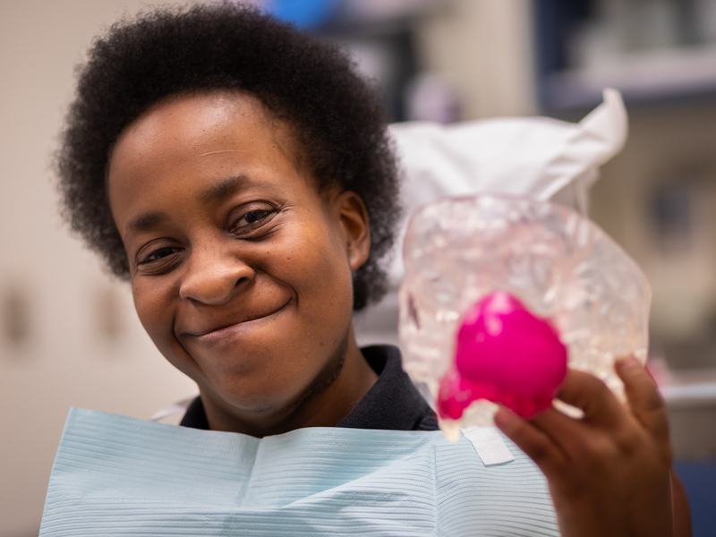 Violet Thompson holds the model showing her head before the tumor was removed.