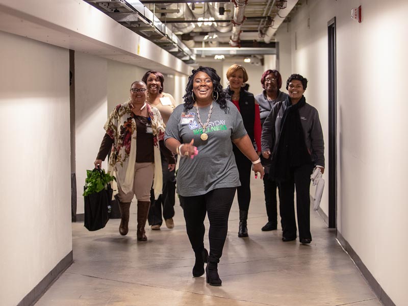 Makeba Harris, center, a billing specialist and wellness champion, walks coworkers through a tunnel at the Clinton Billing Office.