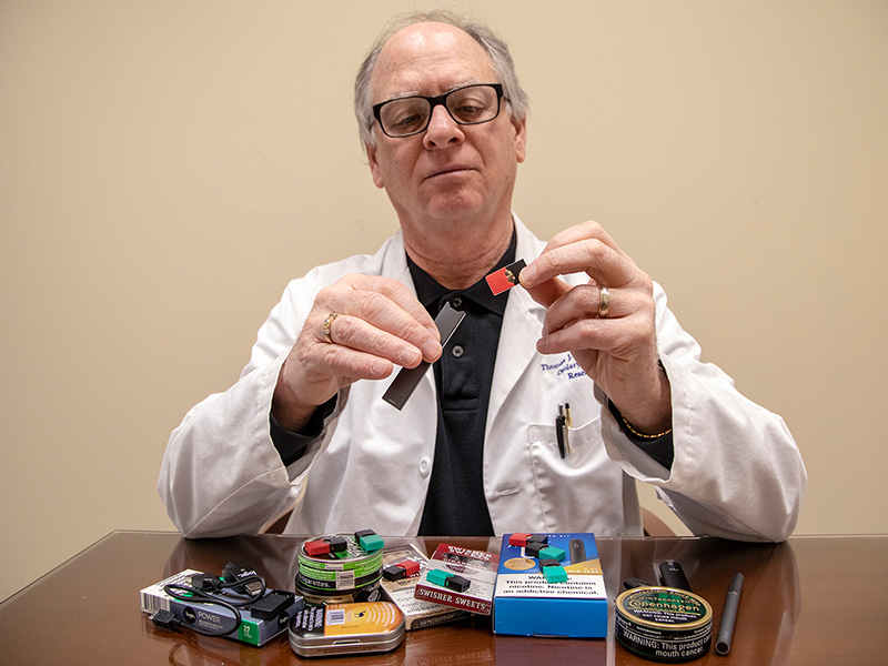 Dr. Thomas Payne, professor of otolaryngology and communicative sciences and director of the ACT Center for Tobacco Treatment, Education and Research, explains how an e-cigarette in the shape of a flash drive is used.