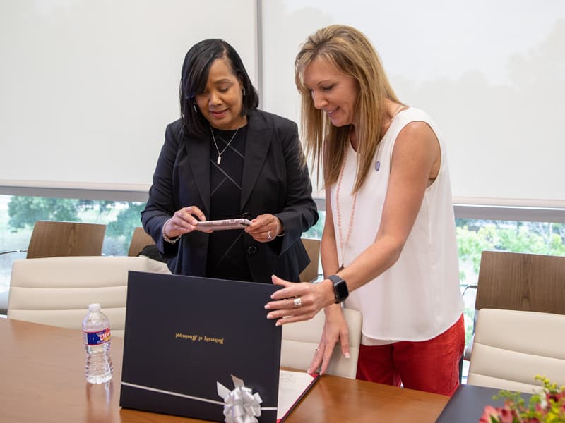 Dr. Bettina Beech, dean of the School of Population Health, takes a photo of Lorie Ramsey's diploma. Ramsey is one of the first three graduates from the school's executive masters in population health management.