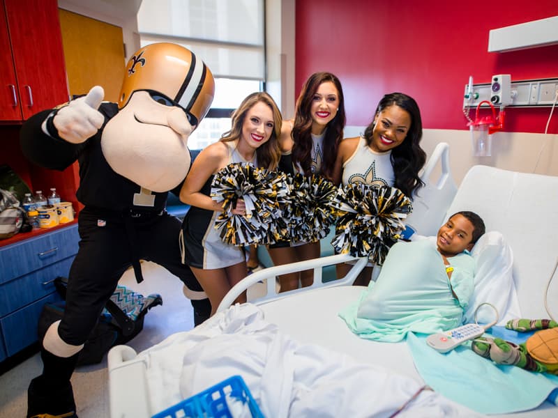 Children's of Mississippi patient Johnny Roper of D'Iberville gets a surprise visit from Sir Saint and Saintsations Kassidi, Rachel, and Kianna.