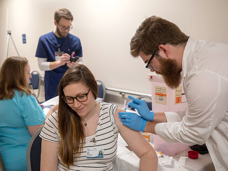 Anna Barnes, left, physical therapist, is armed against the flu with a vaccination from Austin Fitts, third-year pharmacy student.