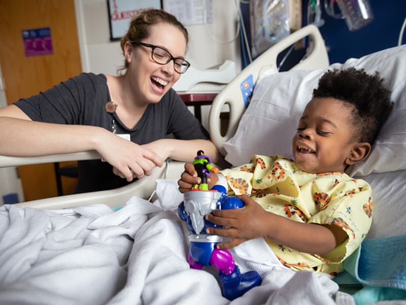 Madeline Wilson, Children's of Mississippi Child Life specialist, laughs with Keidron Hall of Gulfport during his hospital stay.