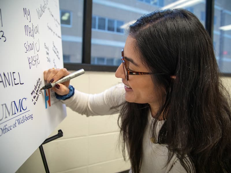 Ruhi Randhawa, a School of Medicine student, writes that she's grateful for her education and the opportunity to serve on a poster near classroom R153. The poster is sponsored by several UMMC groups, including the Office of Well-being.