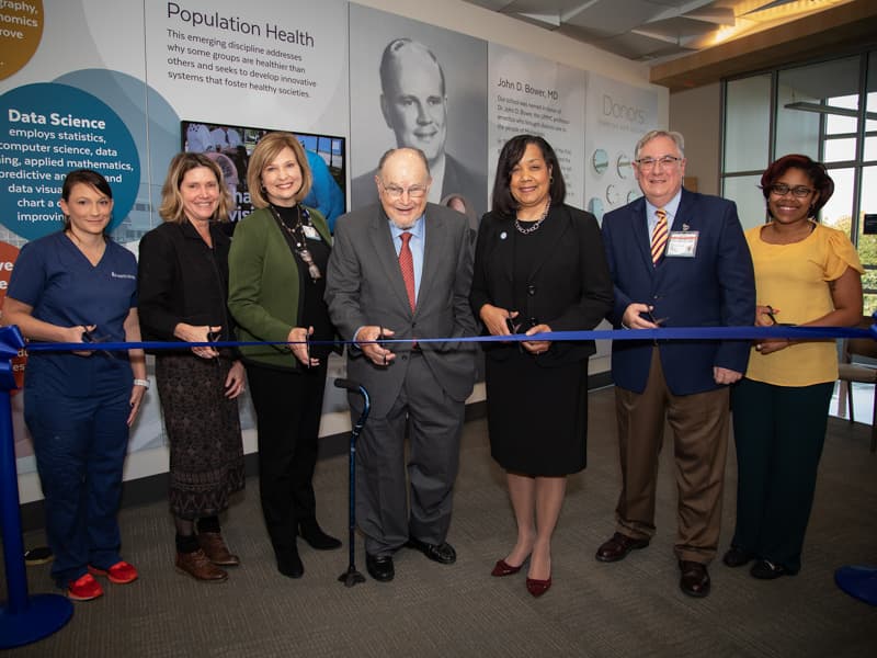 Cutting the ribbon during the John D. Bower School of Population Health's open house include, from left, Dawn McLendon, SOPH student; Anne Travis, Bower Foundation CEO; Dr. LouAnn Woodward, UMMC vice chancellor for health affairs; Dr. John Bower, professor emeritus of medicine and first leader of the Bower Foundation; Dr. Bettina Beech, founding dean of the SOPH; Dr. Ralph Didlake, UMMC associate vice chancellor for academic affairs; and Courtney Gomilia, SOPH student.