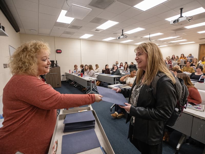 Rhonda Donald, education administrator in the School of Nursing, hands information to incoming student Teresa Moncrief.