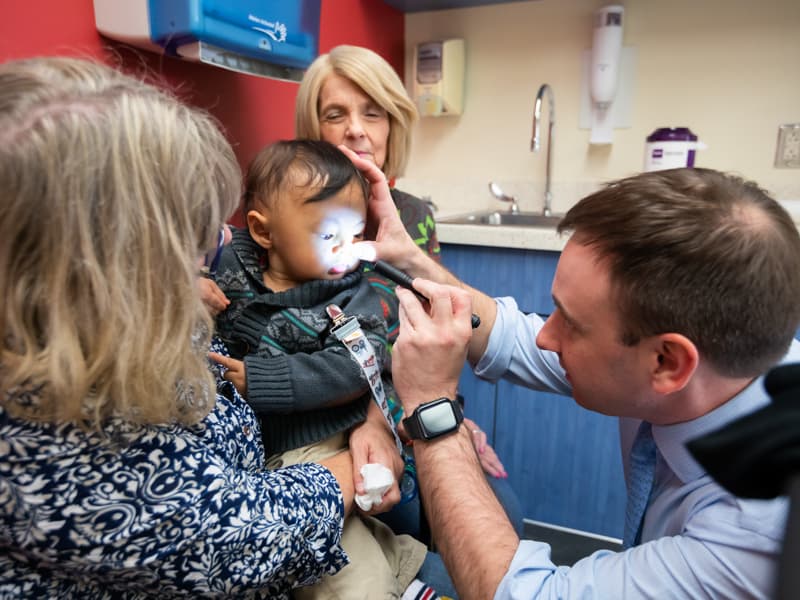 Dr. Ian Hoppe examines Scotty Virak's nasal area while Scotty's mother, Alli Mellon, and his grandmother, Barbara Mellon, watch.