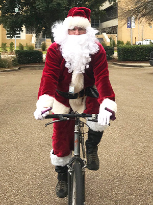 To stay fit, Santa Claus rides a bicycle to his pre-Christmas Eve appearances, including the UMMC Gingerbread Village Competition.