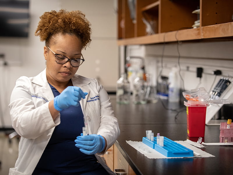 Portrait of Malinda McBride in laboratory with a blood sample in hand.