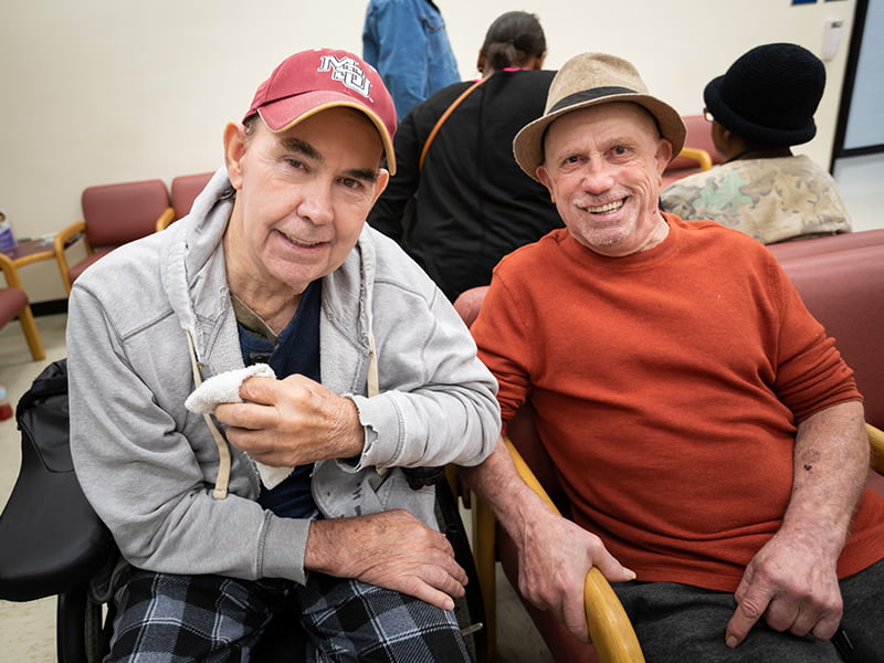 Two patients show off their new dentures.