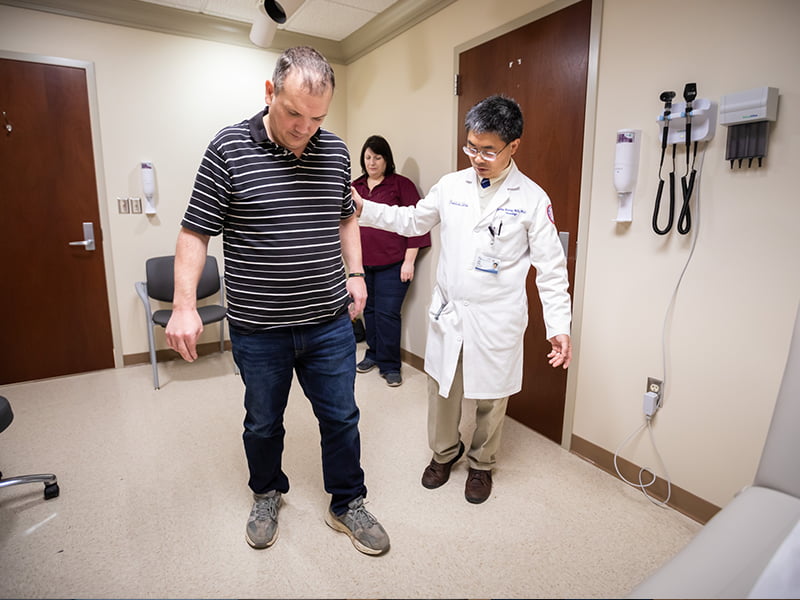 While his wife, Heather, watches, Nathan Wilmoth, a Huntington's disease patient, walks with Dr. Juebin Huang, UMMC associate professor of neurology.
