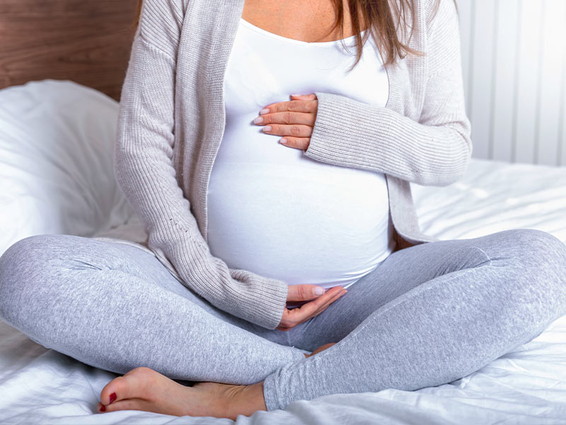 Pregnant woman holds stomach.