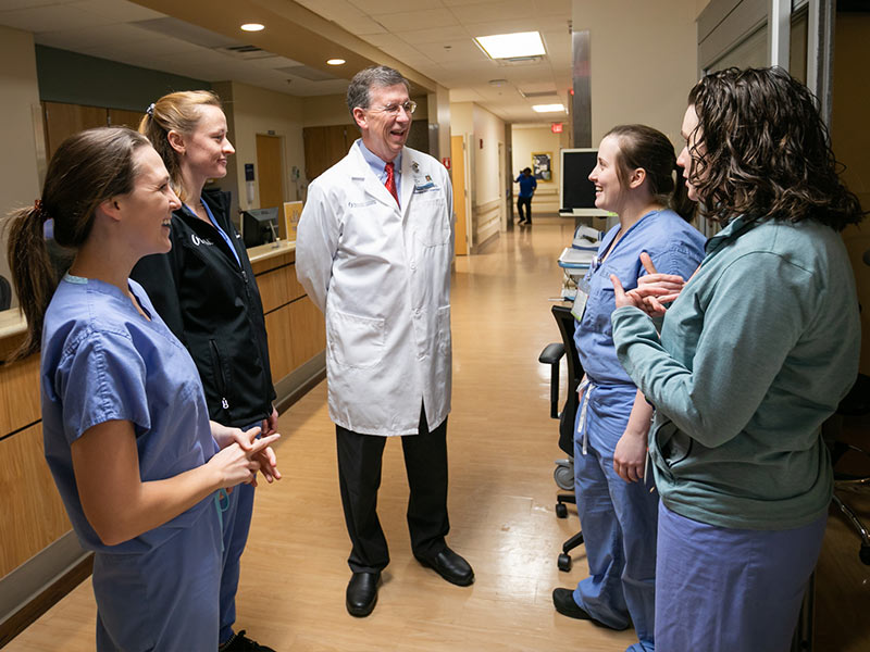 Doctor talking to group of medical students in hallway.