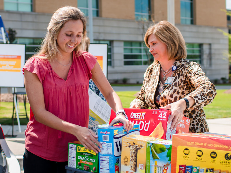 Olivia Woodward, left, and her mom, Dr. LouAnn Woodward, vice chancellor for health affairs and dean of the School of Medicine, hand off donations for COVID-19 relief at the Medical Center at a dropoff station in front of the School of Medicine.