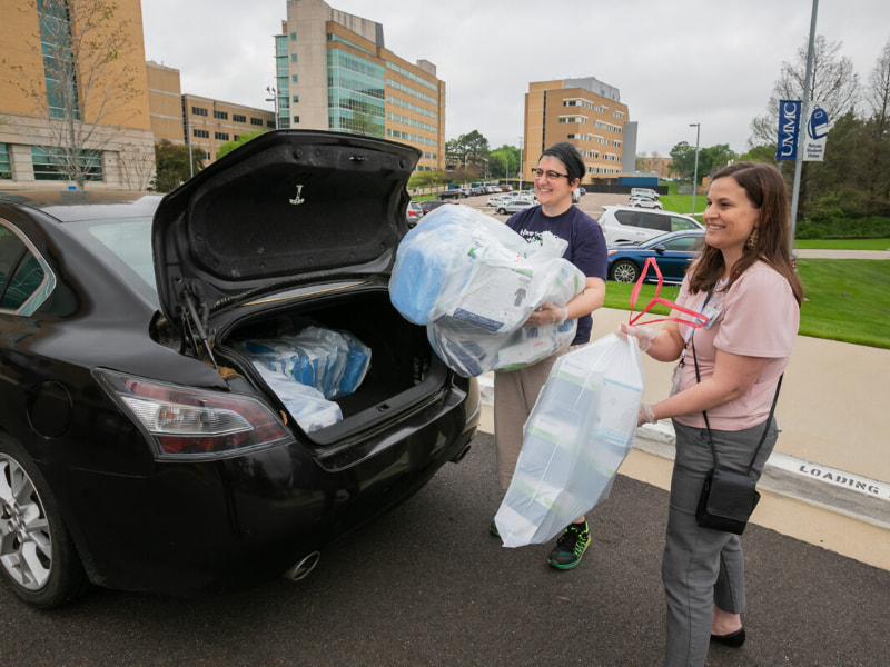Keri Henley, right, UMMC associate executive director of development, helps Nina Ghaffari, a volunteer assisting Mississippi Spay and Neuter, unload donated surgical masks for the hospital's front-line caregivers.