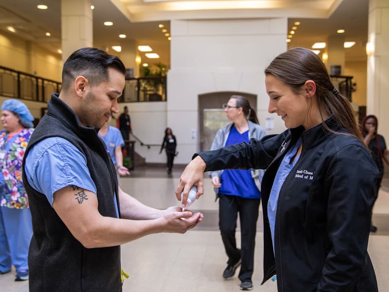 First-year medical student Sarah Dulske, right, offers hand sanitizer to Zeke Gonzalez, chairman of the COVID-19 Student Response Coordination Team. Dulske is a team leader in the group.