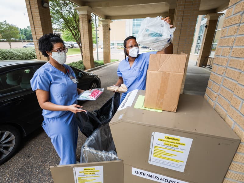 Ashley Brown and Jeshanah Johnson collect donated COVID-19 supplies from a drop box.