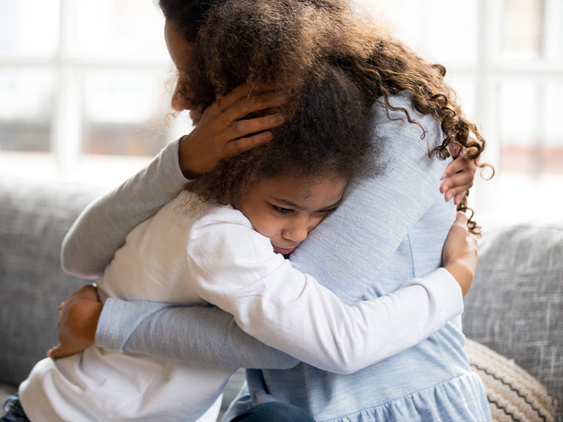 Mother hugging daughter.