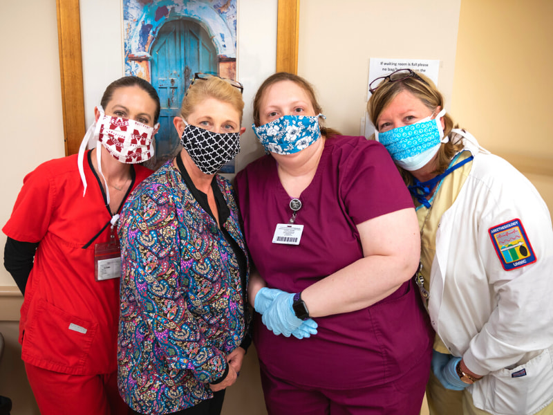 Modeling homemade masks with vibrant patterns are, from left, Emily Smith, ophthalmic technologist; Leigh Kelly, ophthalmic surgery technician; Chynna Martin, ophthalmic technician; and Heidi Johnson, nurse.