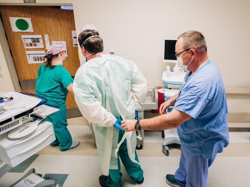 2 North nurse manager Jamie Hill, right, helps a fellow nurse don personal protective equipment before entering the room of a COVID-19 patient.