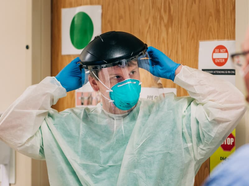 Registered nurse Jacob Ellett prepares to enter a COVID-19 patient's room on 2 North.