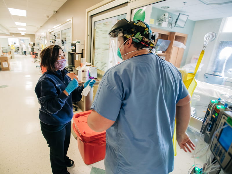 Ashley Moore, MICU nurse manager, goes over the care of COVID-19 patients with Will Parish, nurse.