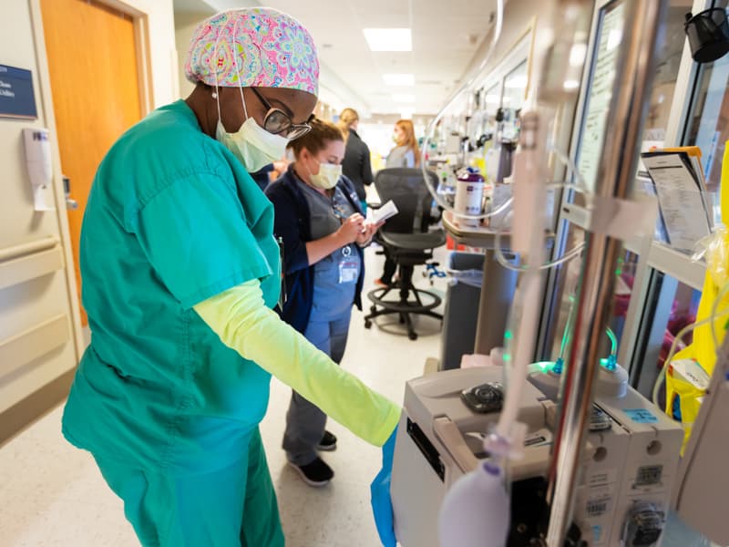 Registered nurse Clair Thompson Huffman checks equipment pulled just outside a COVID-19 patient's room on the medical ICU.