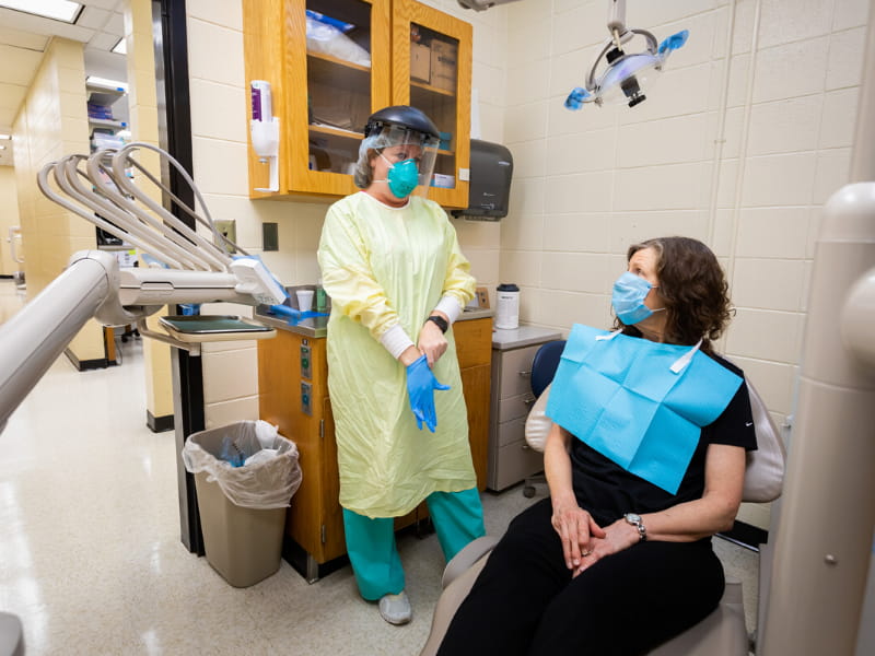 Tiffany Tompkins, dental hygienist, dons her personal protective equipment before Betty Vinson's routine cleaning.