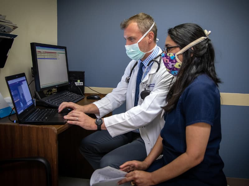 Dr. Will Campbell, a cardiologist with University Heart, and Marlene Holloway, a registered nurse care coordinator, visit with a patient via telehealth.