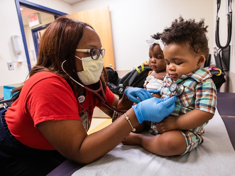 Dr. Anza Stanley listens to Zavi Jackson's heartbeat while his twin sister, Zuri, watches.