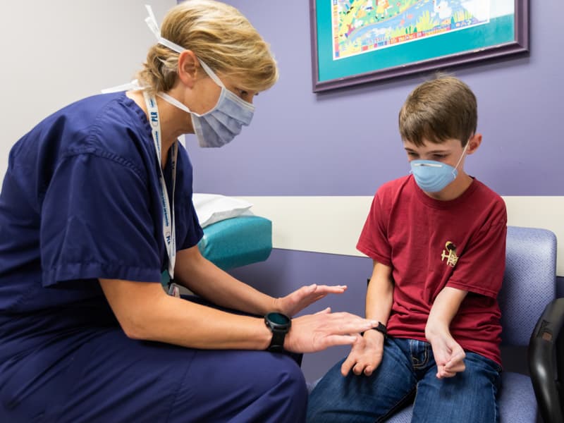 Dr. Kellie Leitch takes a look at patient Hunter Lindsay's hands and forearms during a follow-up visit.