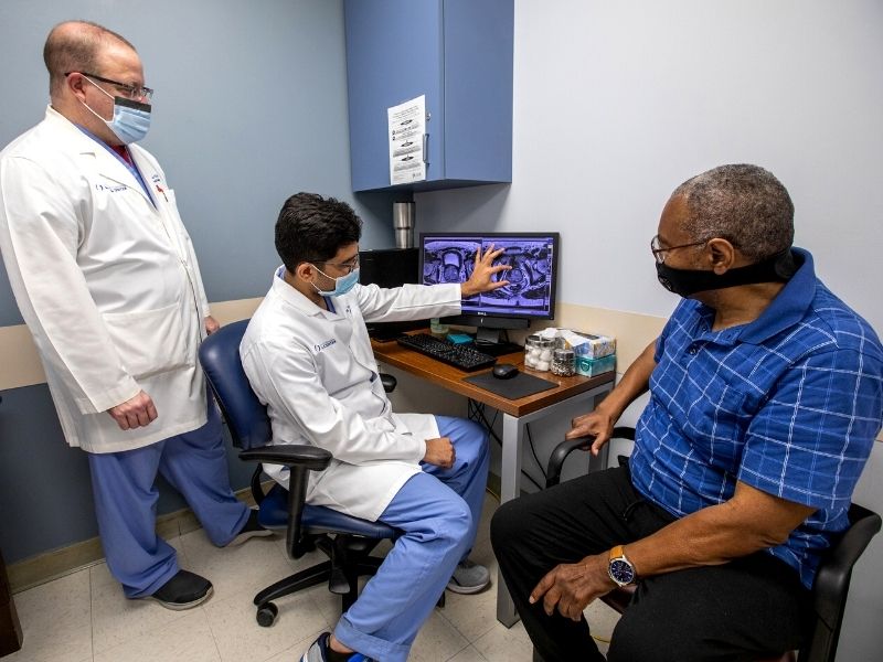 Nurse practitioner Mark Duncan, left, interventional radiologist Dr. Jay Vasani and patient Raleigh Bogan discuss Bogan's progress following surgery.