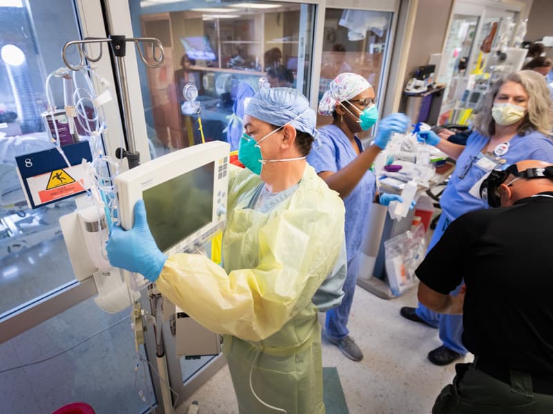 David Mitchell, respiratory therapist, checks a COVID-19 patient's ventilator in the ICU.