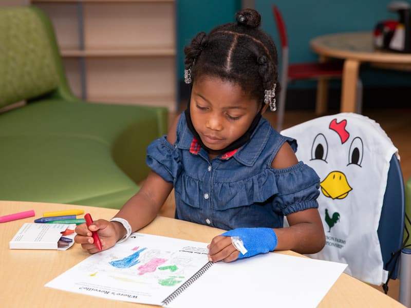 Jakia Jones of Vicksburg, a Children's of Mississippi patient, colors a page in the Sanderson Farms Championship activity book included in the tournament backpack given to patients.