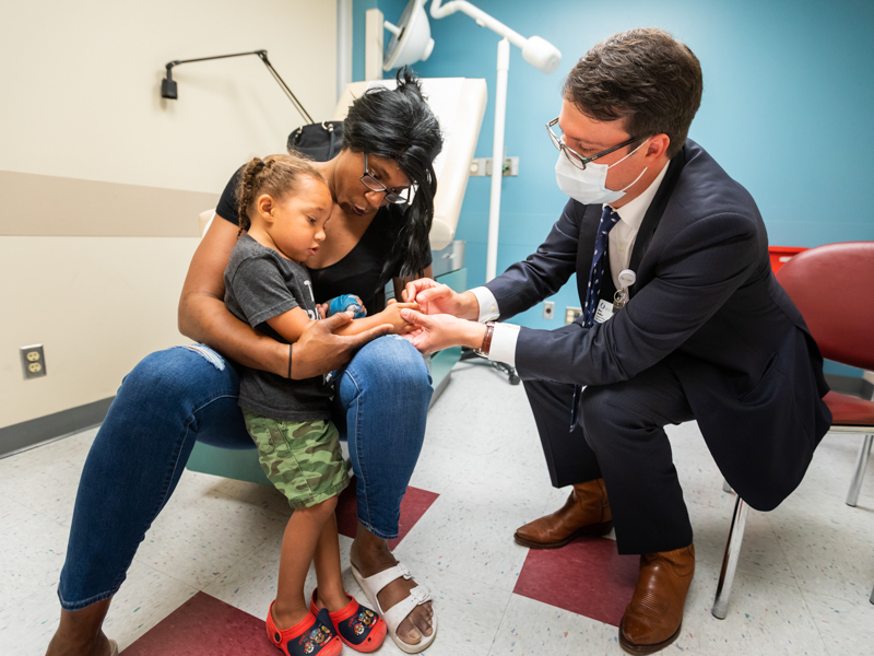 Chantel Strahan holds her son, Xavier, while Dr. Marc Walker looks at Xavier's hand post-surgery in this photo taken in June.